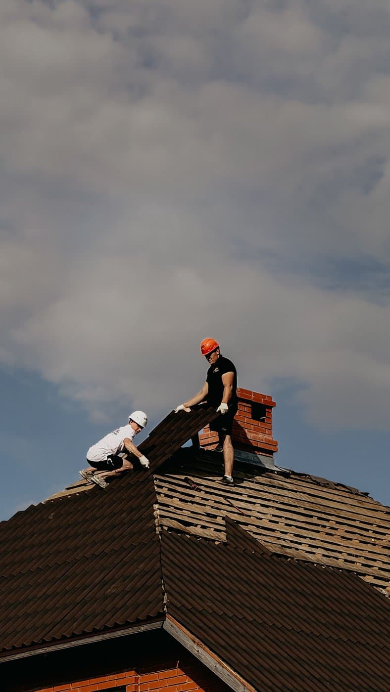Two roofing contractors installing shingles on a residential roof